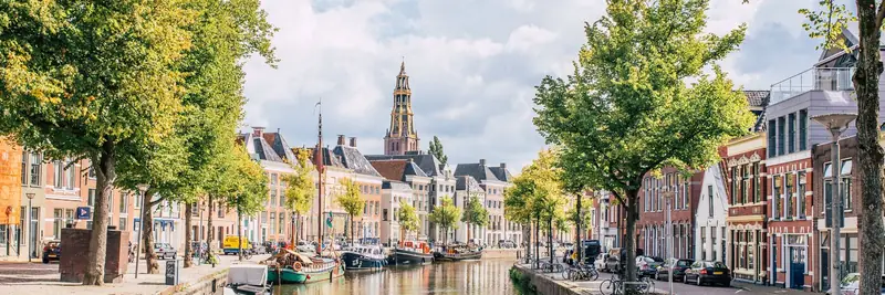 De Hoge der A in Groningen, met woonboten in het water en de toren van de Der Aa-kerk op de achtergrond